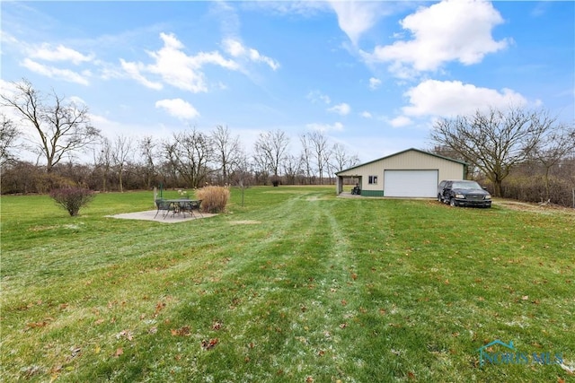 view of yard featuring a garage, an outdoor structure, and a patio area