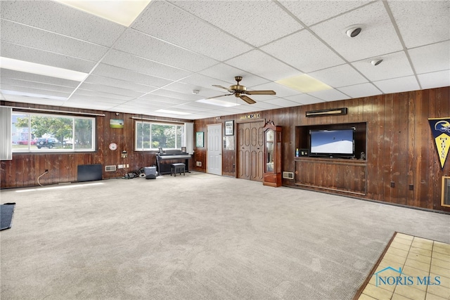 unfurnished living room featuring a paneled ceiling, ceiling fan, and carpet floors