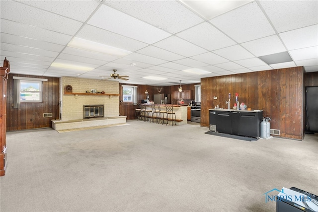 unfurnished living room featuring ceiling fan, a fireplace, and a drop ceiling