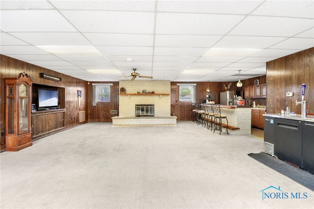 carpeted living room with a paneled ceiling, ceiling fan, and a brick fireplace