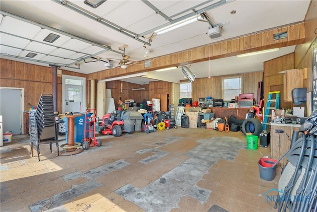 garage with ceiling fan, a garage door opener, and wooden walls