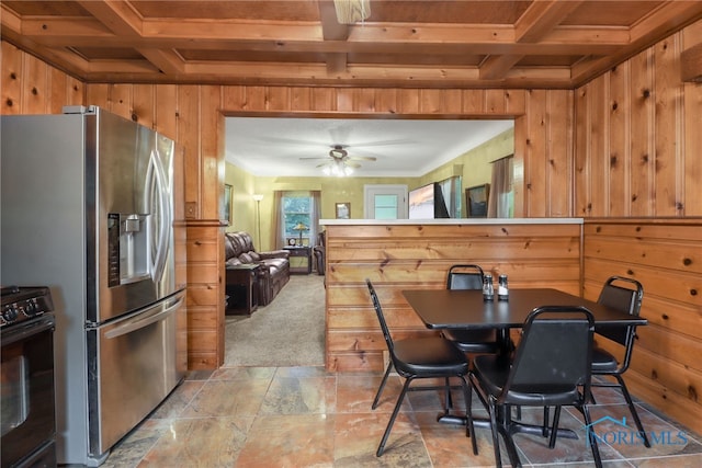 dining room featuring ceiling fan, wood walls, and beam ceiling