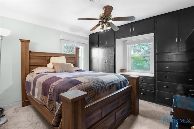 bedroom with ceiling fan, light colored carpet, and multiple windows