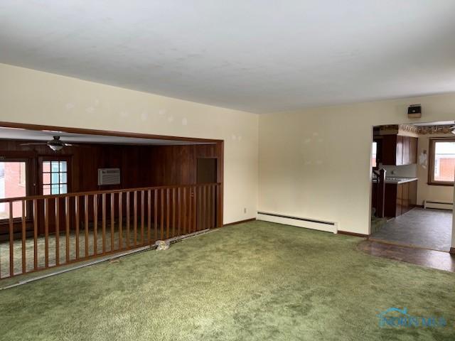 carpeted spare room with ceiling fan and a baseboard radiator