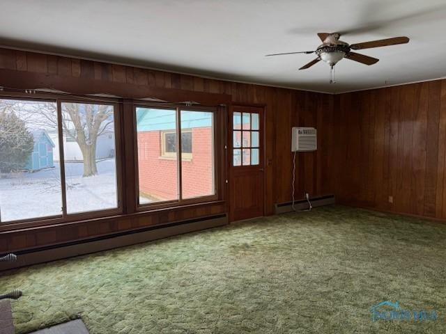 interior space featuring carpet floors, baseboard heating, wooden walls, and ceiling fan