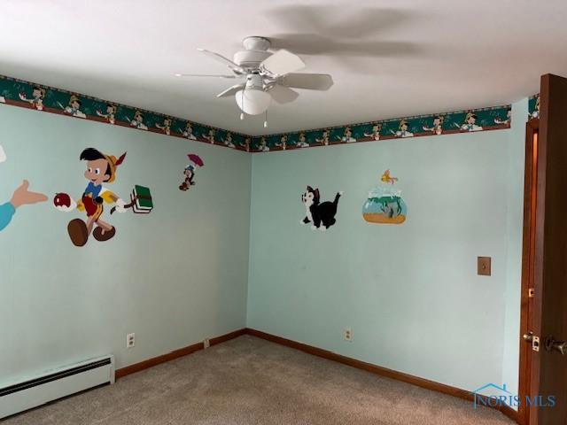 carpeted spare room featuring baseboard heating and ceiling fan