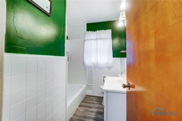 full bathroom with vanity,  shower combination, tile walls, hardwood / wood-style floors, and toilet