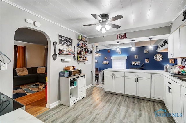 kitchen featuring ceiling fan, white cabinets, hanging light fixtures, and light wood-type flooring