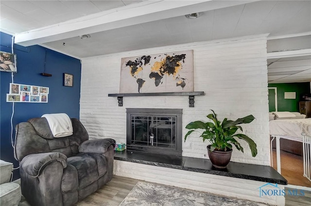 living room with beamed ceiling, wood-type flooring, and a fireplace