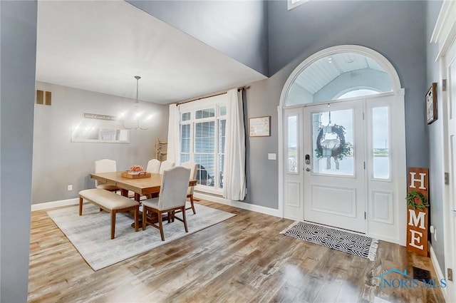 foyer entrance featuring a chandelier, light wood-type flooring, and high vaulted ceiling