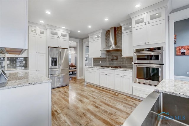 kitchen with white cabinets, stainless steel appliances, and wall chimney range hood