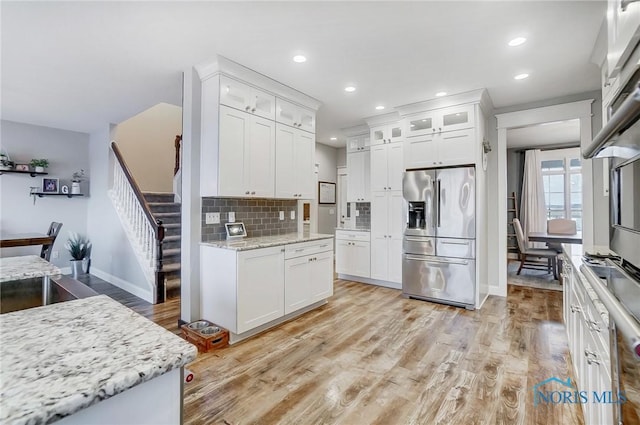 kitchen with white cabinetry, light stone countertops, stainless steel fridge with ice dispenser, and backsplash