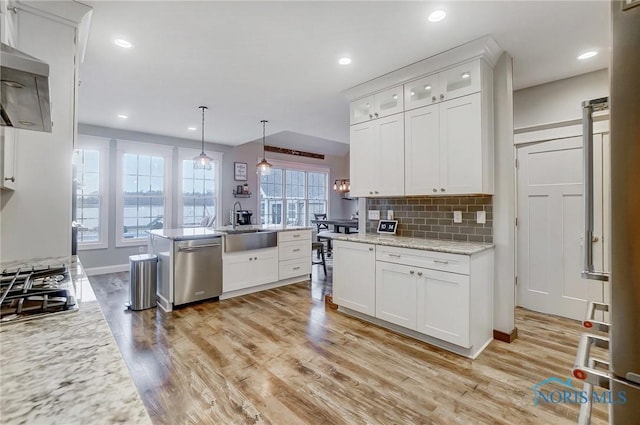 kitchen featuring backsplash, hanging light fixtures, light hardwood / wood-style flooring, white cabinetry, and stainless steel appliances