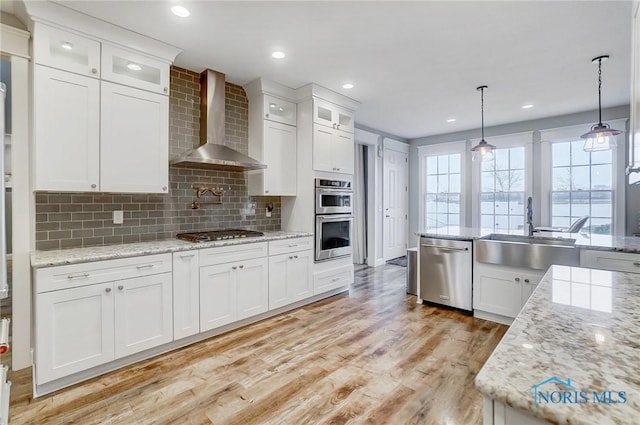 kitchen with white cabinets, wall chimney range hood, and appliances with stainless steel finishes