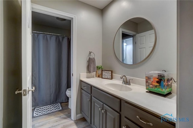 bathroom featuring hardwood / wood-style flooring, vanity, a shower with shower curtain, and toilet