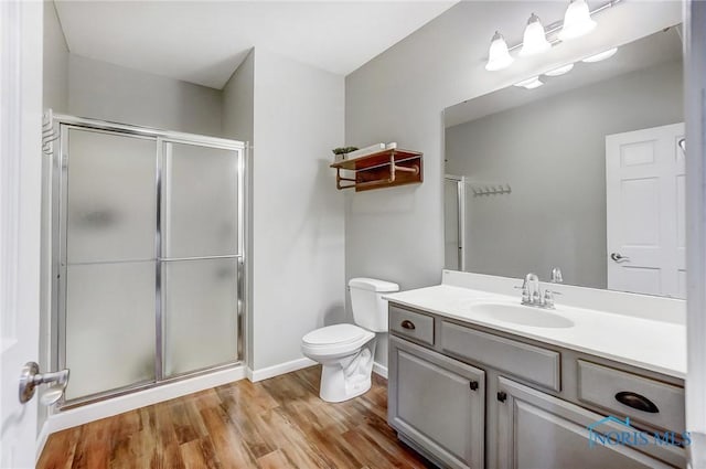 bathroom with vanity, hardwood / wood-style flooring, toilet, and a shower with door