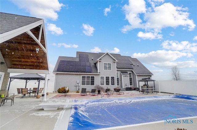 back of property with solar panels, a patio, and a gazebo