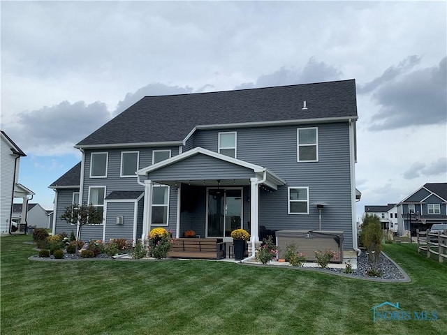 rear view of house featuring a lawn, a hot tub, and a patio