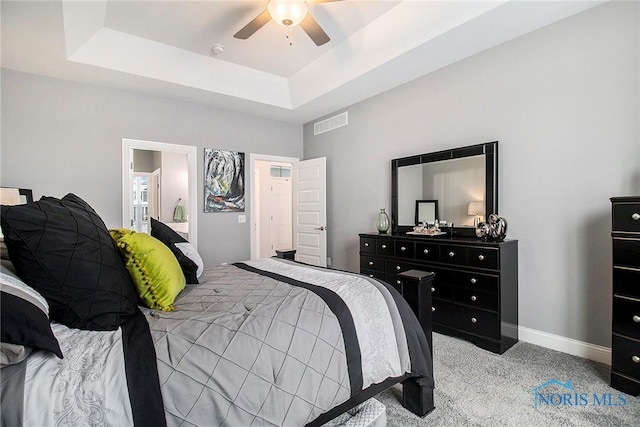 carpeted bedroom with a raised ceiling and ceiling fan