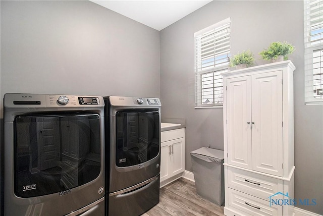 laundry area featuring separate washer and dryer, light hardwood / wood-style floors, and cabinets