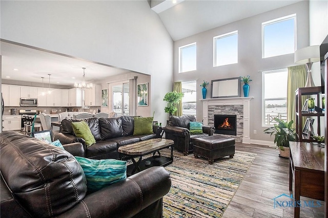 living room featuring a stone fireplace, an inviting chandelier, and light wood-type flooring