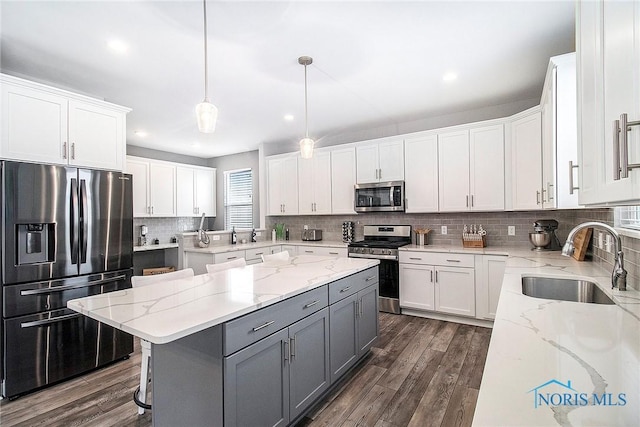 kitchen featuring sink, gray cabinetry, hanging light fixtures, stainless steel appliances, and white cabinets