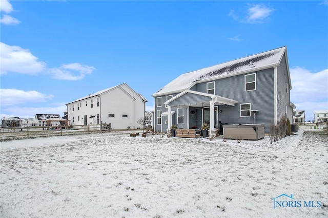 snow covered property featuring central AC and a hot tub