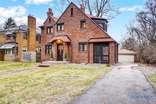 tudor-style house featuring an outbuilding, a garage, and a front yard