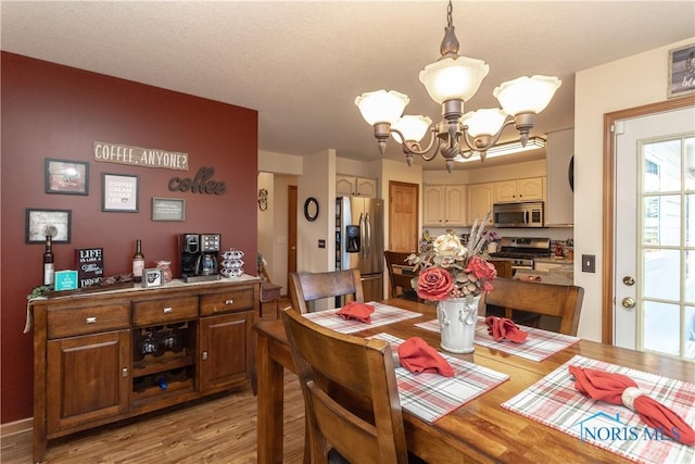 dining space with light hardwood / wood-style floors and an inviting chandelier