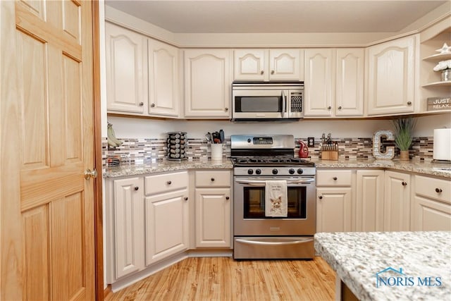 kitchen with light stone countertops, stainless steel appliances, and light hardwood / wood-style flooring