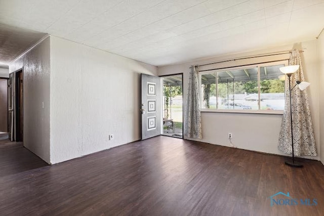 unfurnished room with dark wood-type flooring