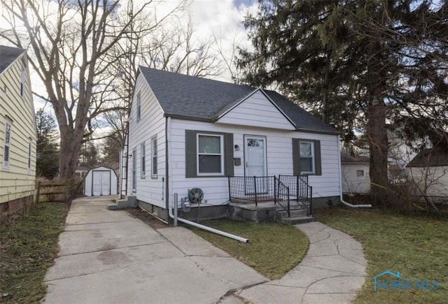 bungalow with a garage, an outbuilding, and a front lawn