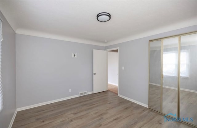 unfurnished bedroom featuring wood-type flooring and a closet