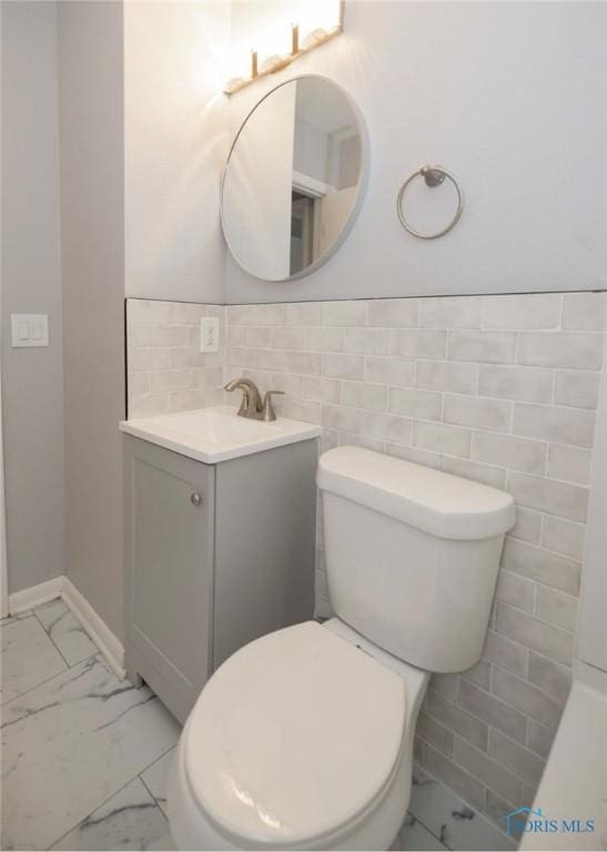 bathroom with vanity, toilet, and tile walls