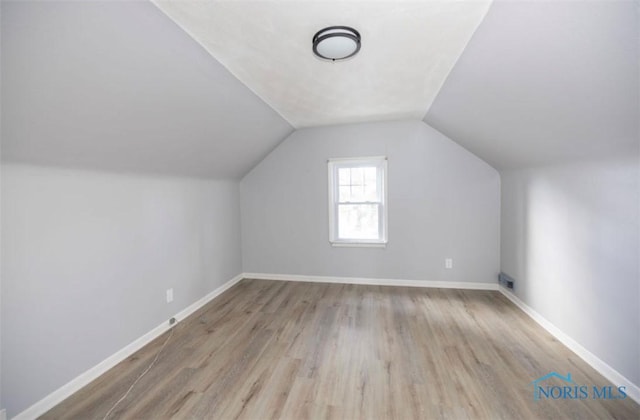 bonus room with lofted ceiling and light wood-type flooring