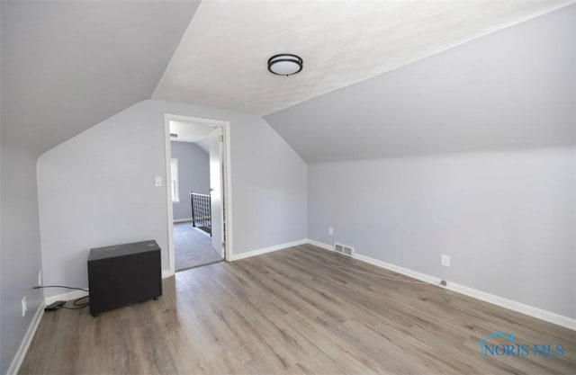 bonus room with light hardwood / wood-style floors and vaulted ceiling