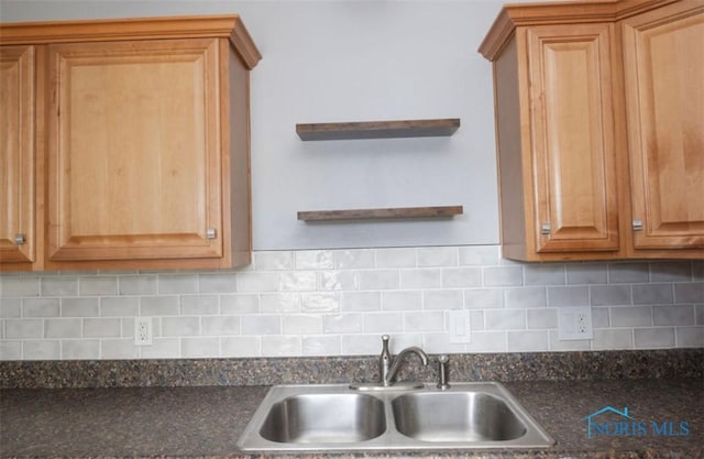 kitchen with dark stone countertops, decorative backsplash, and sink