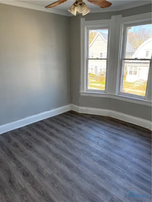 unfurnished room featuring dark hardwood / wood-style floors, ceiling fan, and crown molding