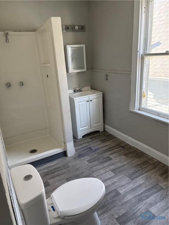 bathroom with hardwood / wood-style floors, vanity, toilet, and walk in shower