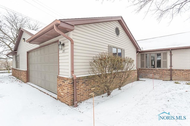 view of snow covered exterior featuring a garage