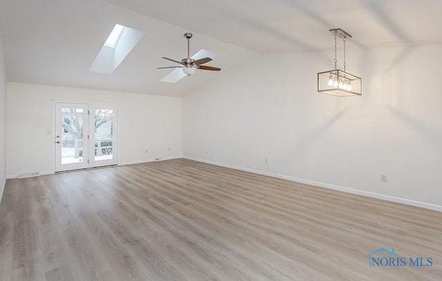 interior space featuring ceiling fan, lofted ceiling with skylight, and light hardwood / wood-style flooring