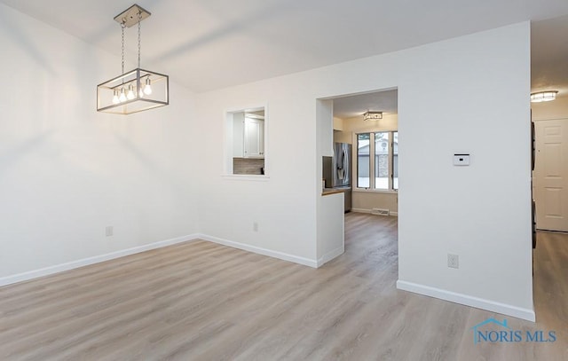 unfurnished dining area featuring light hardwood / wood-style floors and a chandelier