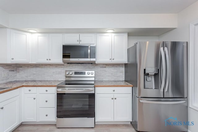 kitchen with white cabinets, light hardwood / wood-style floors, appliances with stainless steel finishes, and tasteful backsplash