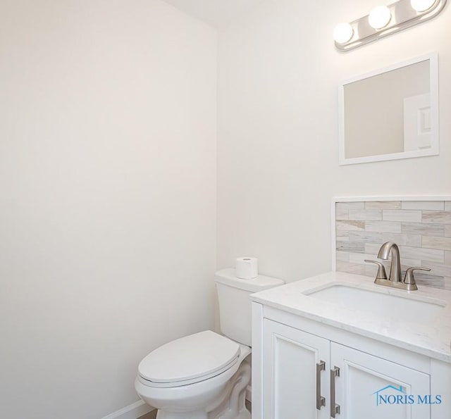 bathroom with backsplash, vanity, and toilet