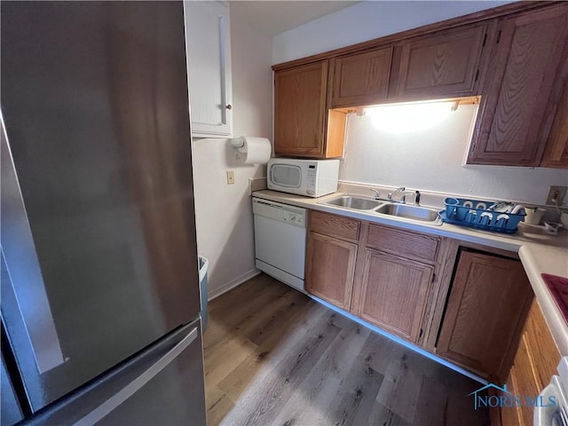 kitchen featuring sink, light hardwood / wood-style floors, and white appliances