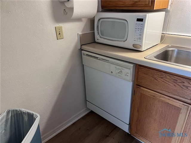 kitchen with white appliances, dark wood-type flooring, and sink