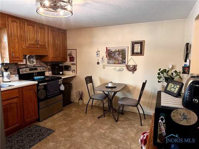 kitchen featuring stainless steel range with electric stovetop, sink, a textured ceiling, and backsplash