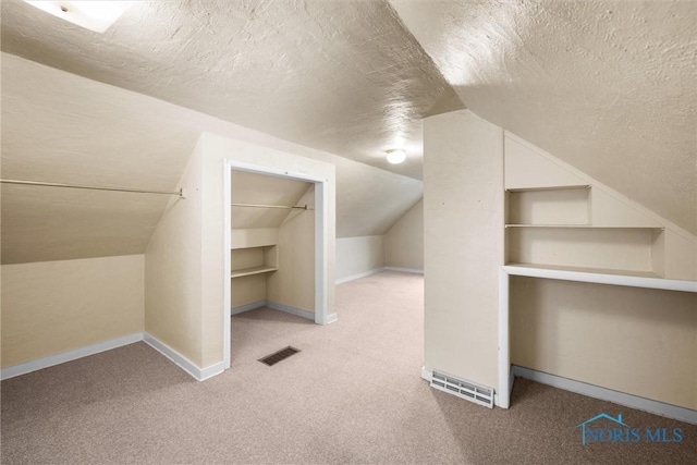 additional living space with light carpet, built in shelves, a textured ceiling, and lofted ceiling