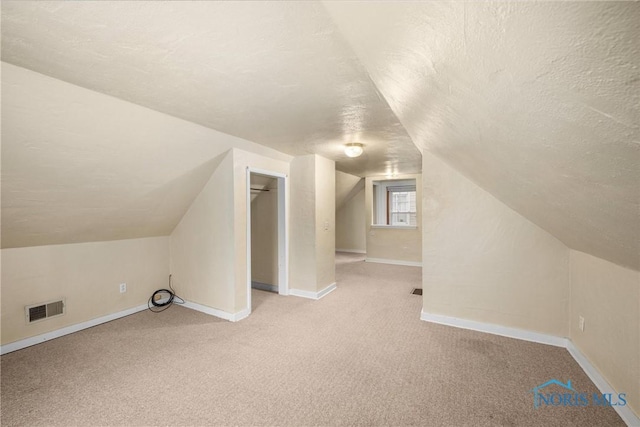 bonus room with light colored carpet, a textured ceiling, and vaulted ceiling