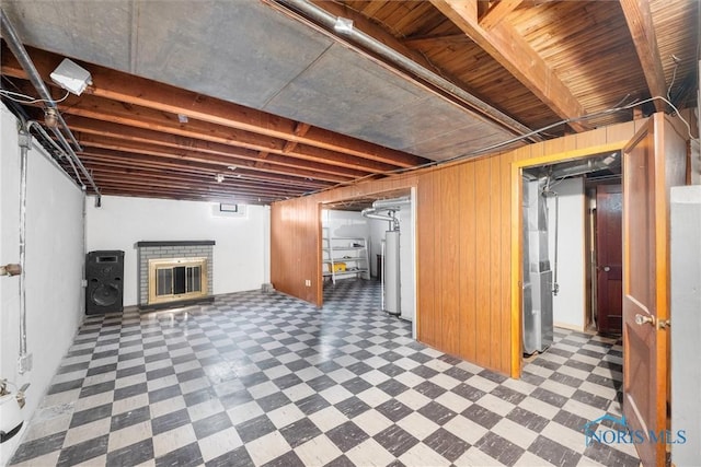 basement with wooden walls, gas water heater, and a brick fireplace